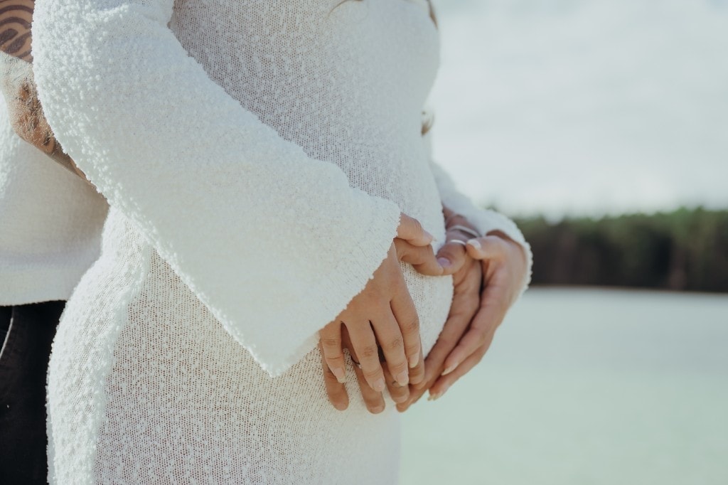 Nahaufnahme vom Babybauch mit Händen am See