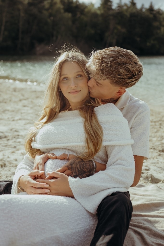 Zärtlicher Kuss beim Babybauchshooting am Strand