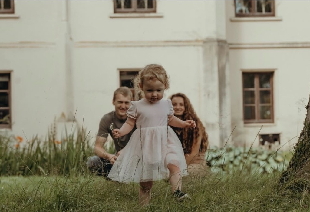 Familie mit Kind im hohen Gras vor historischem Gebäude