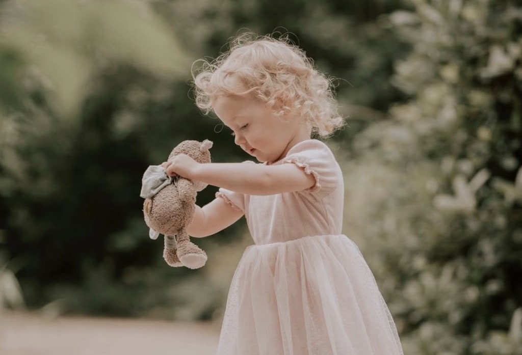 Kind im Profil mit Teddybär im Grünen