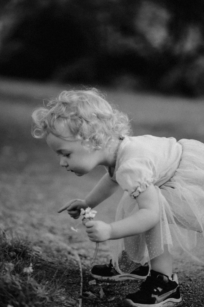 Kind pflückt kleine Blumen am Wegrand