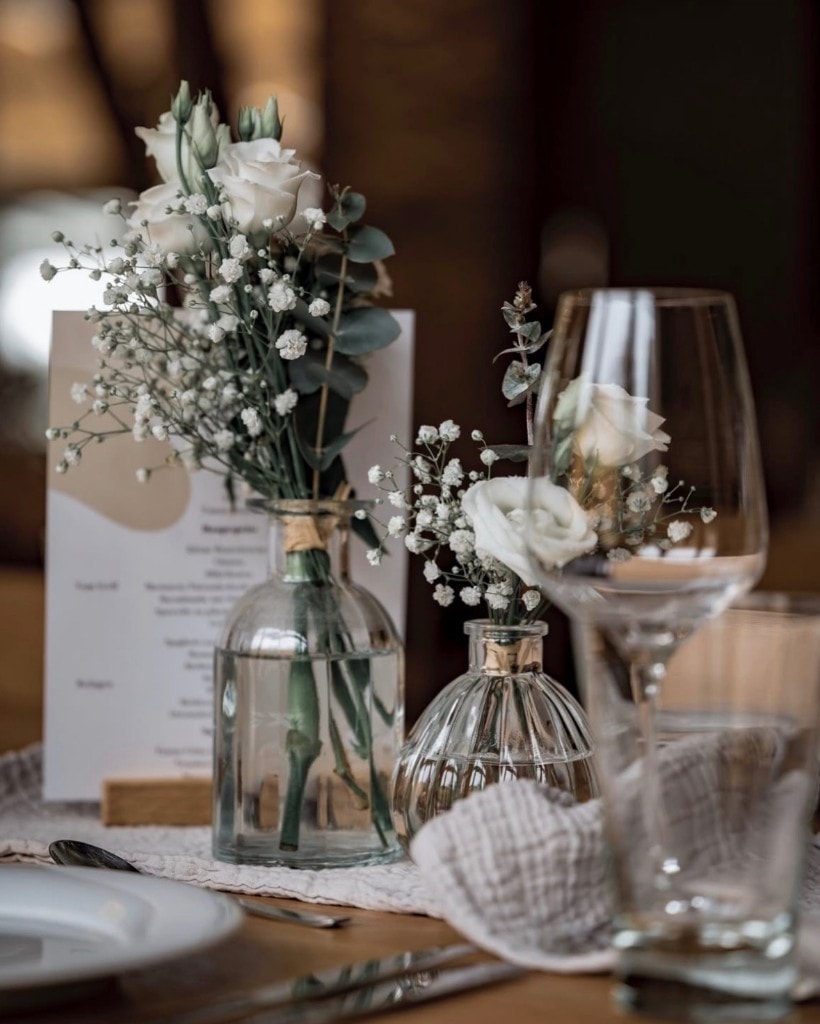 Hochzeitsdekoration mit Blumen und Gläsern