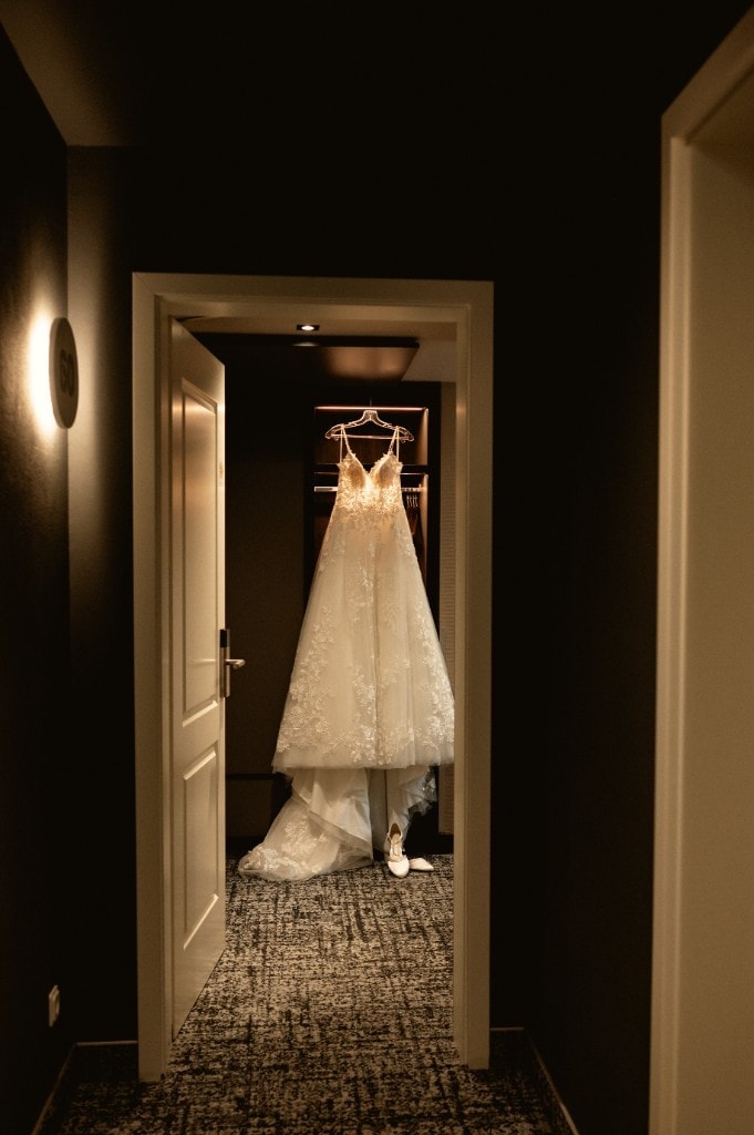 Brautkleid hängt stimmungsvoll im Türrahmen