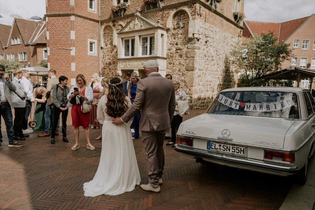 Brautpaar vor dem Standesamt mit Just-Married-Auto
