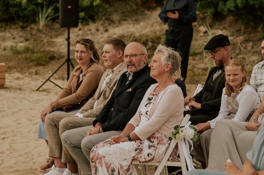 Hochzeitsgäste bei der Trauung im Freien auf Sand