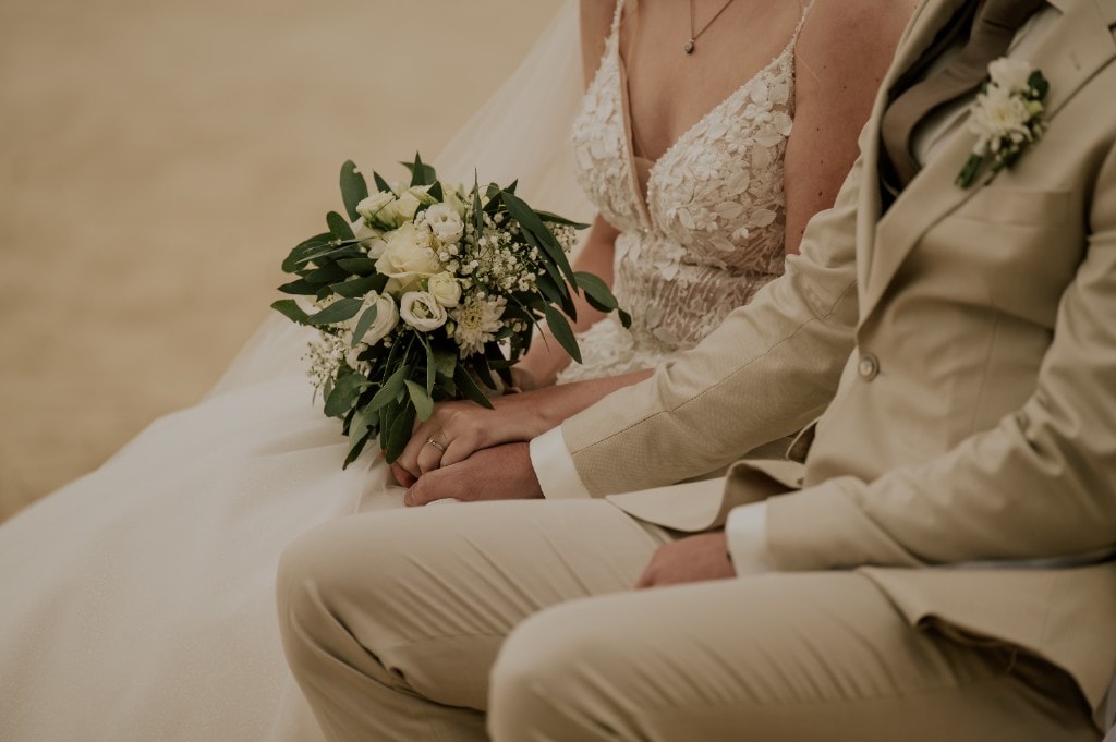 Hände des Brautpaars mit Brautstrauß aus weißen Rosen